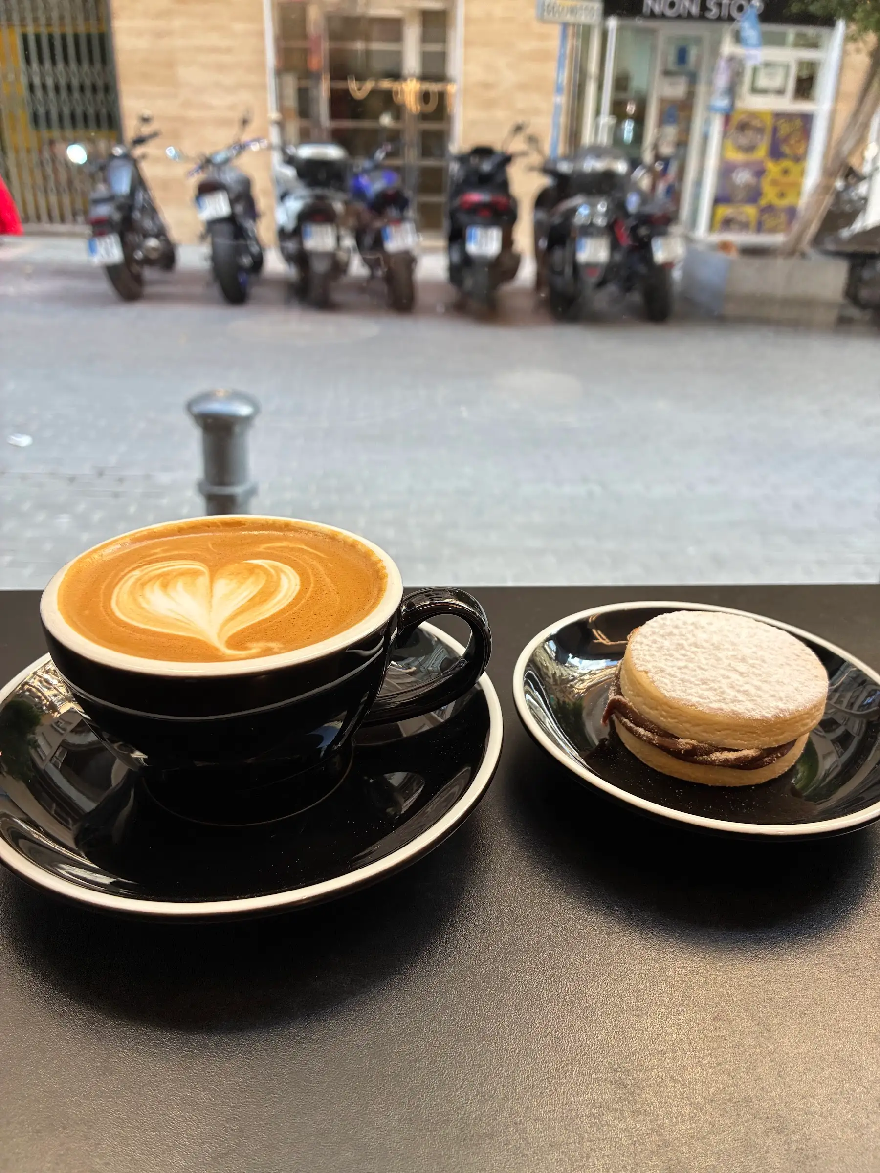 Café con leche y un alfajor en la barra de la ventana