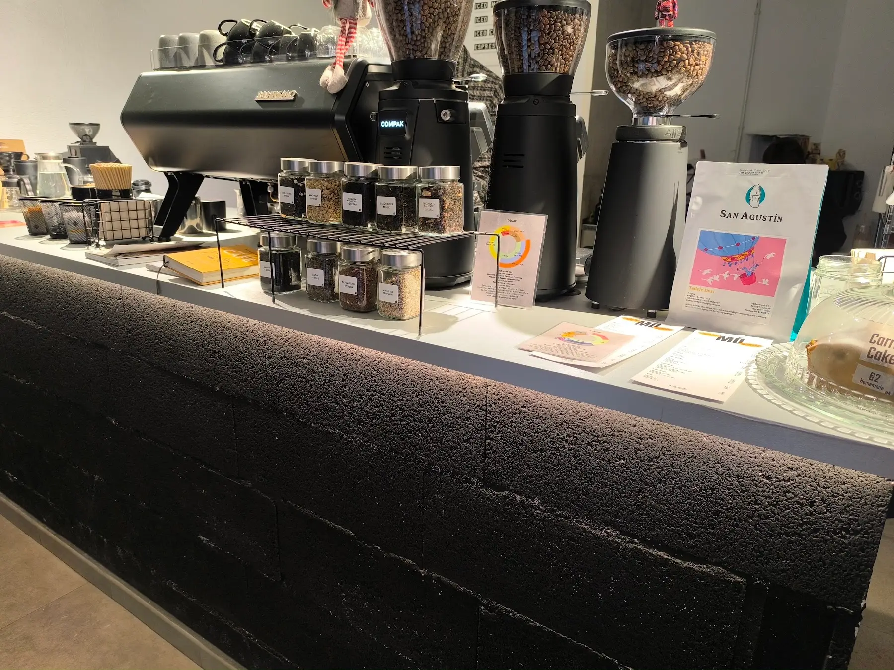 La barra de bloque volcánico negro, la cafetera y los molinos llenos de grano